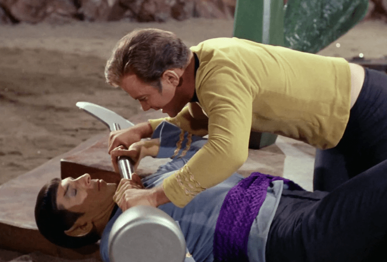 Kirk and Spock grappling on the ground with a traditional Vulcan spear, the lirpa. Kirk's body is on top of Spock's but, like, in a straight way supposedly
