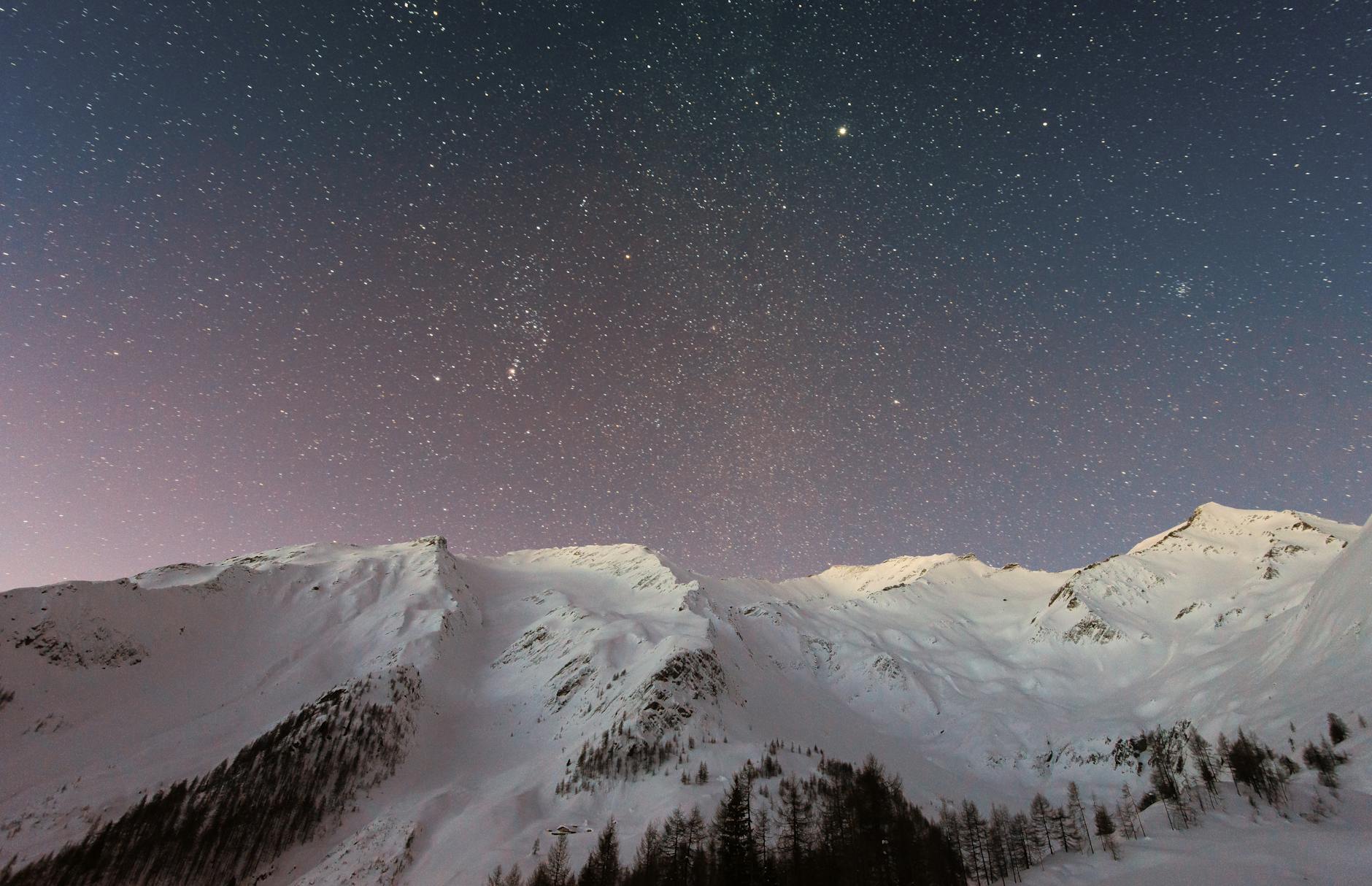 a snowy mountain range with stars overhead